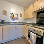 Modern kitchen with oven and hanging pans.