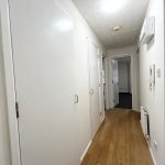 White corridor with wooden flooring and doors