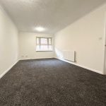 Spacious carpeted room with window and radiator.