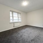 Empty room with grey carpet and window.