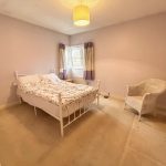 Cosy bedroom with bed, chair, and window curtains.