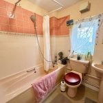 Cosy bathroom with pink tiles and white fixtures.