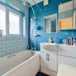 Modern bathroom with blue tiles and white fixtures.