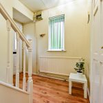 Bright hallway with wooden flooring and white decor.