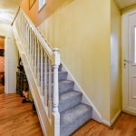 Bright hallway with wooden floors and carpeted stairs.