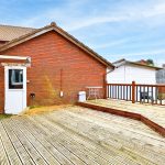 Wooden patio beside brick house, shed visible.