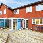 Red brick house with fenced wooden decking area.