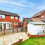 Brick houses with garden and shed in background.