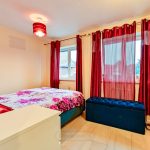 Cosy bedroom with red curtains and floral bedding.