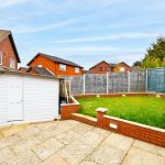 Backyard with lawn, brick walls, and white shed.