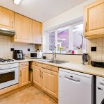 Modern kitchen with light wooden cabinets, appliances.