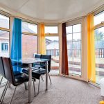 Bright conservatory with colourful blinds and glass table.