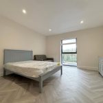 Spacious bedroom with bed and large window view.