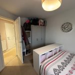 Cosy bedroom with wardrobe and wall clock.