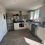 Modern kitchen with appliances and wood flooring.