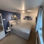 Cosy bedroom with blue accent wall and artwork.