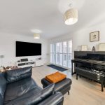 Modern lounge with piano and large TV.