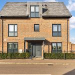 Modern brick house with grey roof and windows.