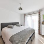 Modern bedroom with grey bed and bright decor.