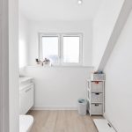 Minimalist modern white bathroom with storage baskets.