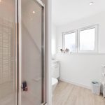 Modern bathroom with shower, window, and storage baskets.