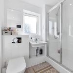 Modern white bathroom with shower and sink.