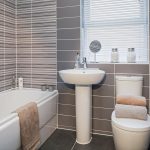 Modern grey-tiled bathroom with bathtub and sink.