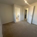 Empty bedroom with en-suite bathroom, beige carpet