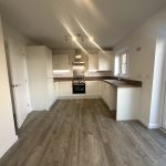 Modern kitchen interior, wood flooring, white cabinets.