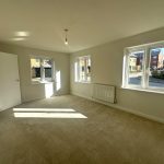 Bright, empty bedroom with windows and radiator