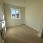 Empty room with beige carpet and window.