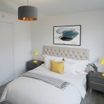 Modern bedroom with grey and yellow accents.