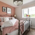 Cosy bedroom with metal bed and pink decor.