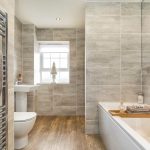 Modern bathroom with grey tiles and wooden flooring.