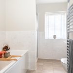 Modern bathroom with bathtub and towel rack.