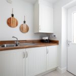 Modern utility room with wooden worktop and sink.