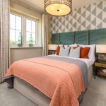 Modern bedroom with patterned wallpaper and orange accents.