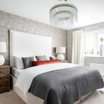 Modern bedroom with chandelier and neutral decor.