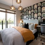 Modern bedroom with colourful wallpaper and window view.