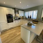 Modern kitchen with white cabinets and wooden floor.