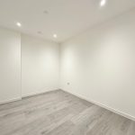 Empty room with wooden flooring and white walls.