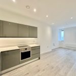 Modern kitchen in spacious flat with wooden floor.