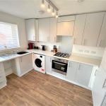 Modern kitchen with white cabinets and wooden floor.