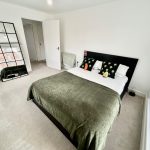 Modern bedroom with mirrors and green accents.