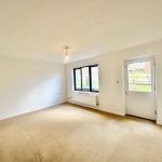 Empty living room with window and door to garden.