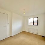 Empty room with beige carpet and window view.