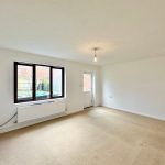 Bright empty room with beige carpet, large window.