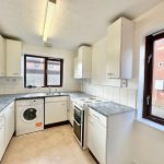 White kitchen with modern appliances and large windows.