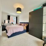 Modern bedroom with double bed and large wardrobe.