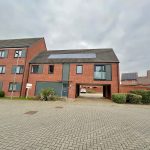 Modern brick house with solar panels and driveway.